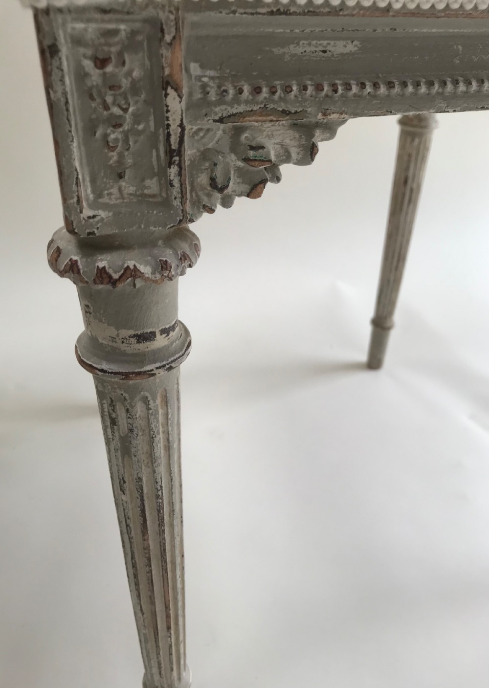 A pair of French Louis XVI style side chairs featuring distressed grey painted wooden frames, carved arcade backrests, and neutral white upholstered seats. View III