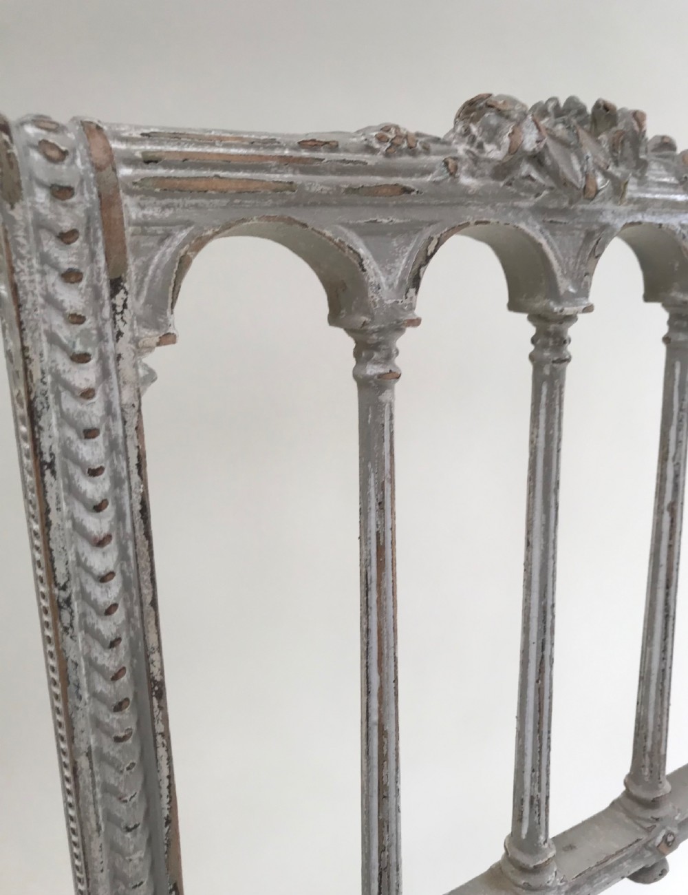 A pair of French Louis XVI style side chairs featuring distressed grey painted wooden frames, carved arcade backrests, and neutral white upholstered seats. View V