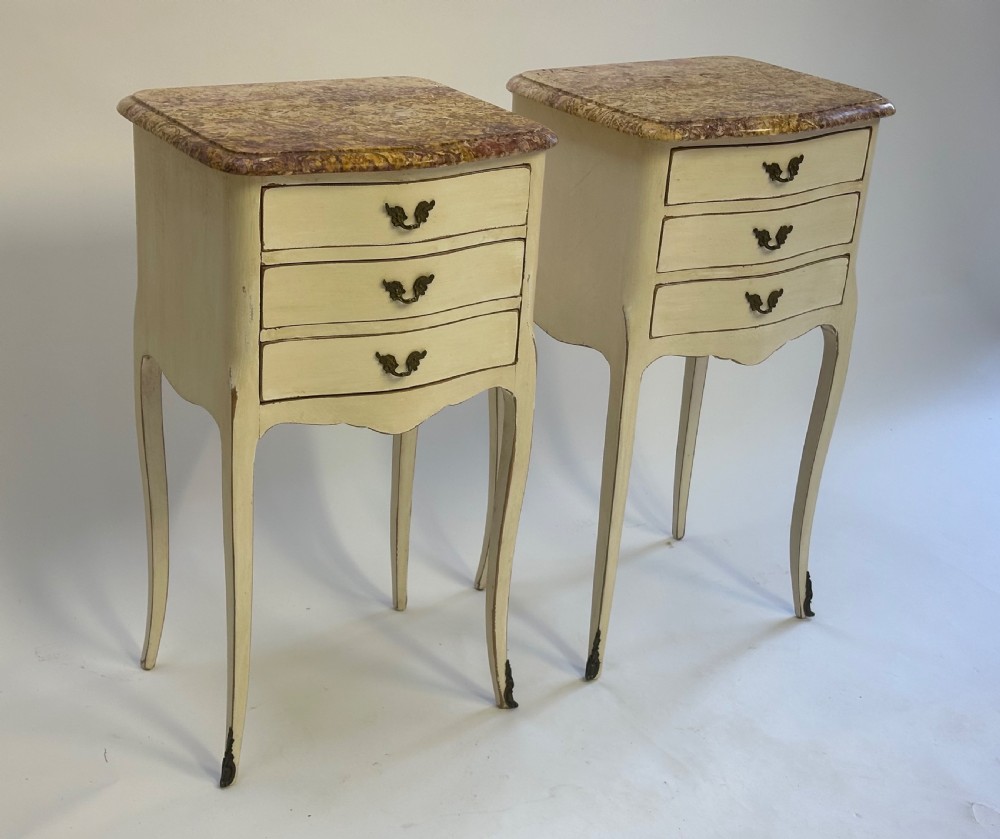 A pair of cream-painted French bedside tables featuring variegated marble tops, three drawers with brass pulls, and slender cabriole legs. View II