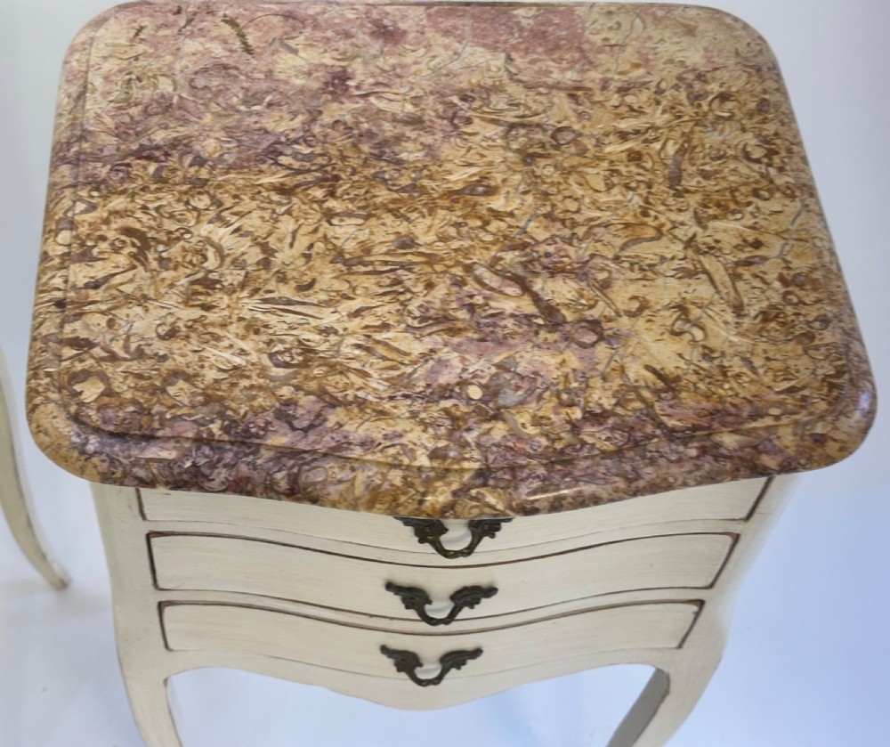 A pair of cream-painted French bedside tables featuring variegated marble tops, three drawers with brass pulls, and slender cabriole legs. View IV