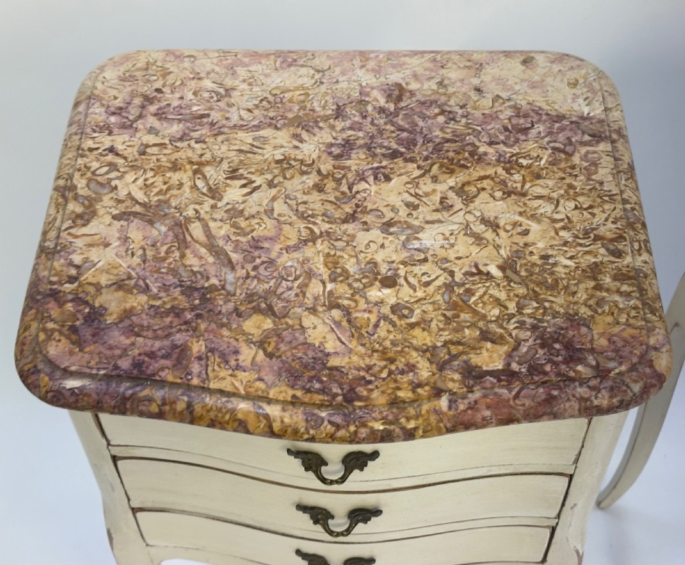 A pair of cream-painted French bedside tables featuring variegated marble tops, three drawers with brass pulls, and slender cabriole legs. View VI