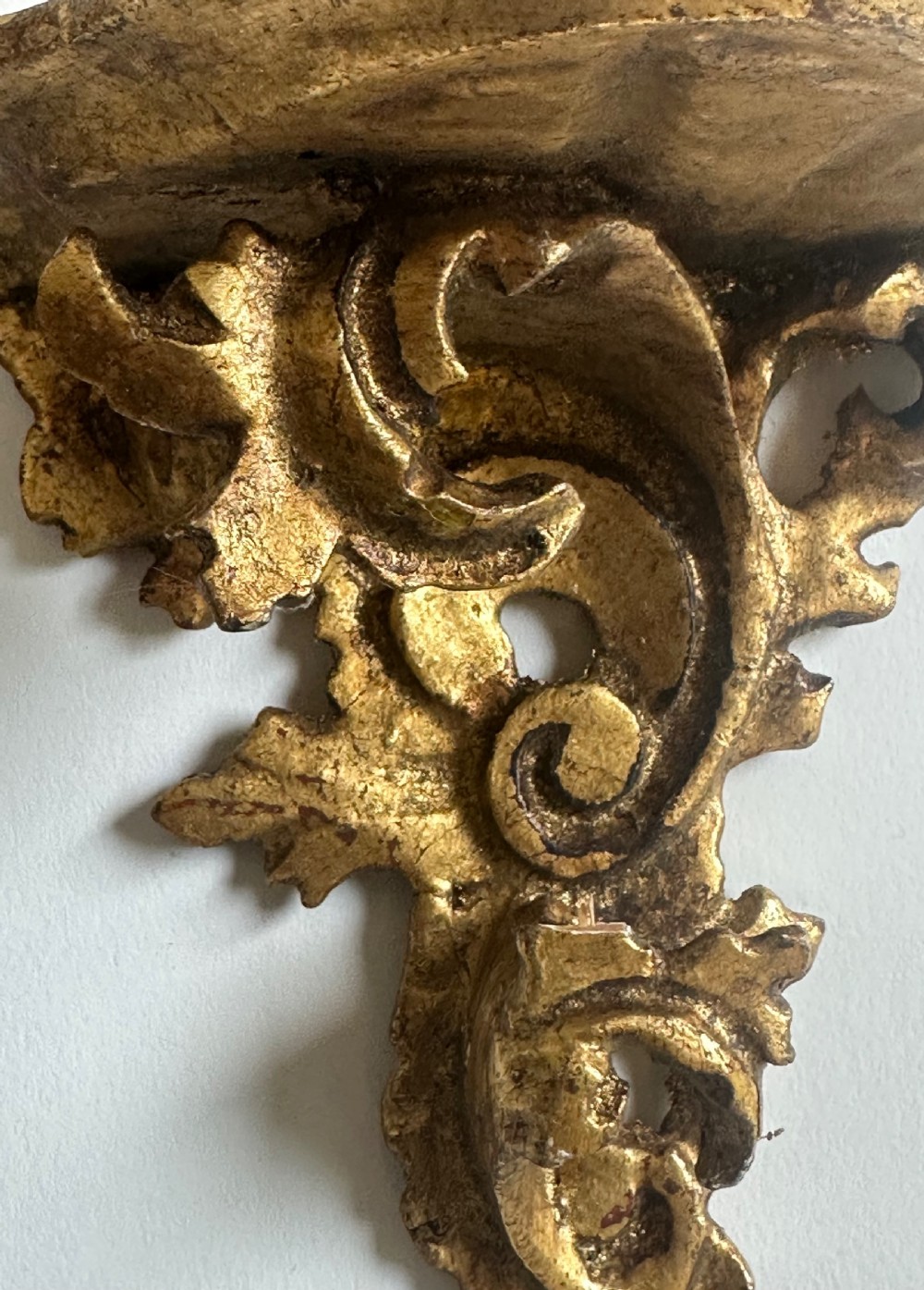A pair of carved wood wall brackets with a hand-gilded gold finish featuring acanthus leaf scrollwork and flat top shelves. View II