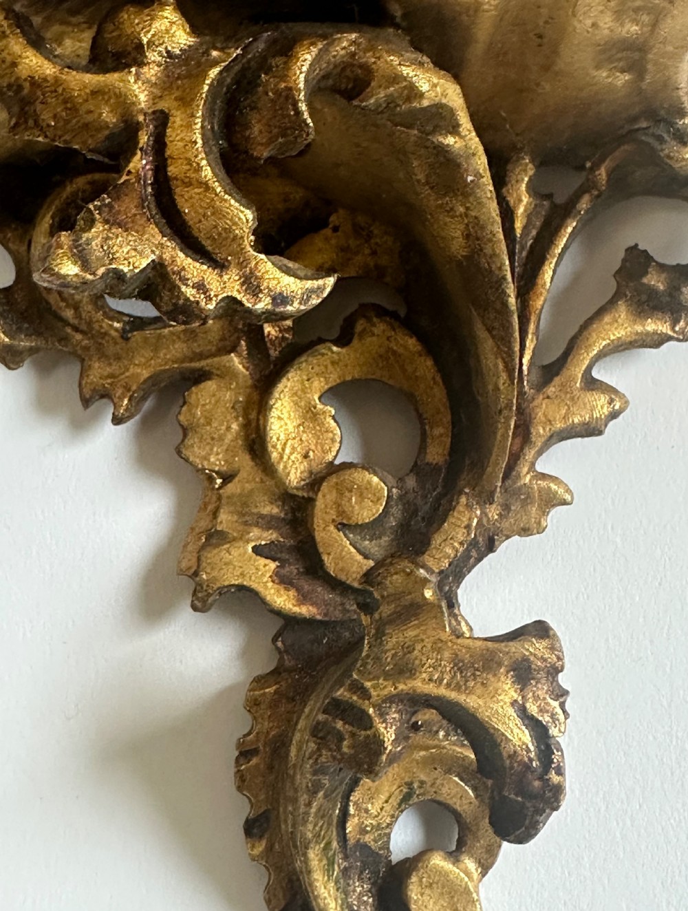 A pair of carved wood wall brackets with a hand-gilded gold finish featuring acanthus leaf scrollwork and flat top shelves. View VI