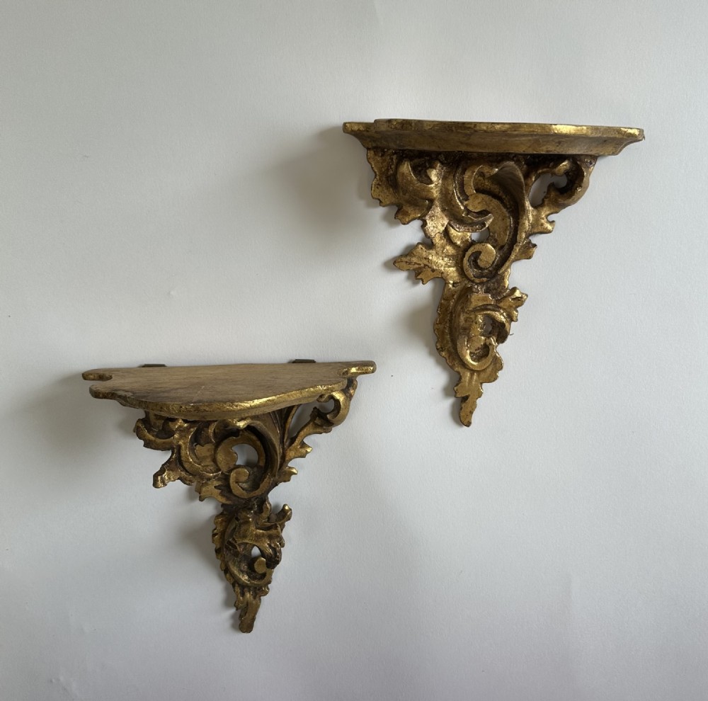 A pair of carved wood wall brackets with a hand-gilded gold finish featuring acanthus leaf scrollwork and flat top shelves. View XI