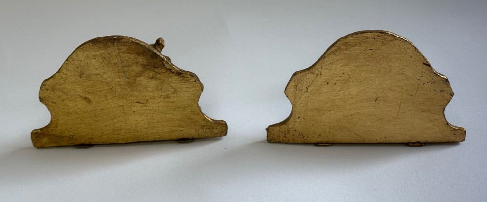 A pair of carved wood wall brackets with a hand-gilded gold finish featuring acanthus leaf scrollwork and flat top shelves. View XV