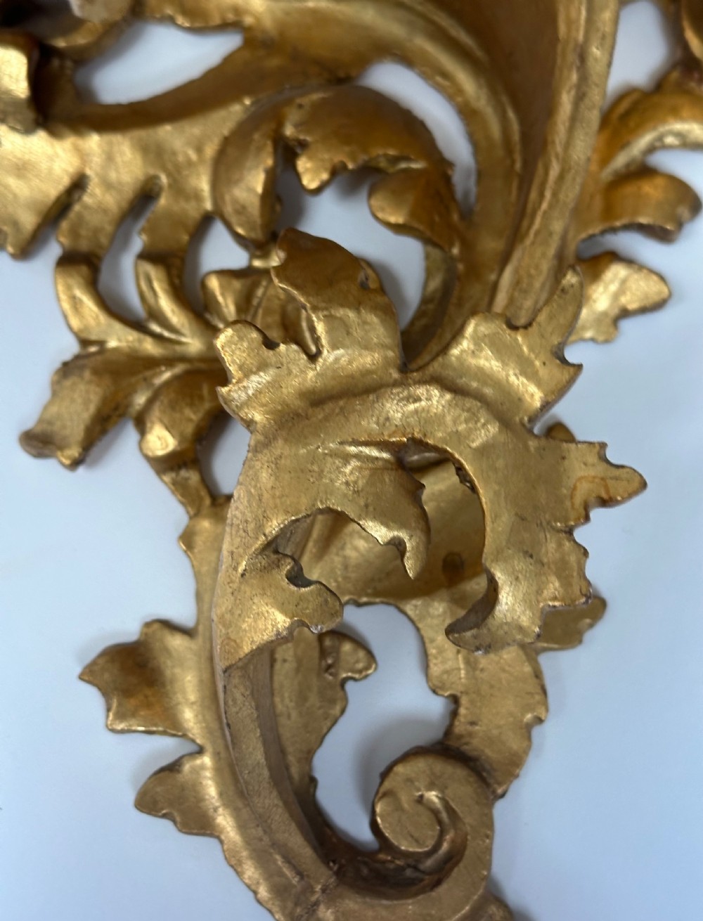 An Italian carved wood wall bracket featuring ornate acanthus leaf scrollwork with a gilded gold leaf finish supporting a semi-circular shelf top. View III