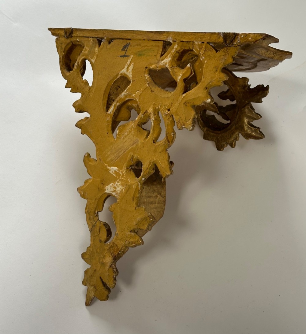 An Italian carved wood wall bracket featuring ornate acanthus leaf scrollwork with a gilded gold leaf finish supporting a semi-circular shelf top. View IV