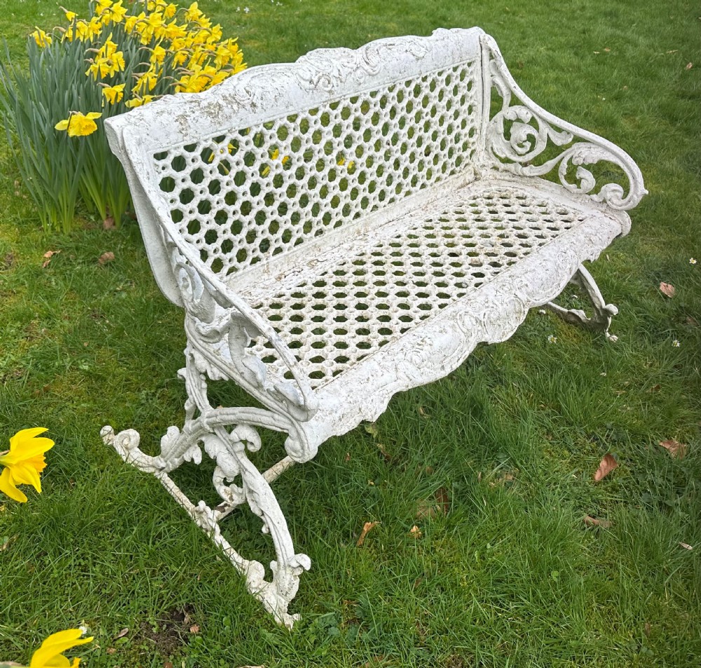 A Victorian white painted cast iron garden bench featuring a pierced lattice backrest and ornate scrolled armrests. View II