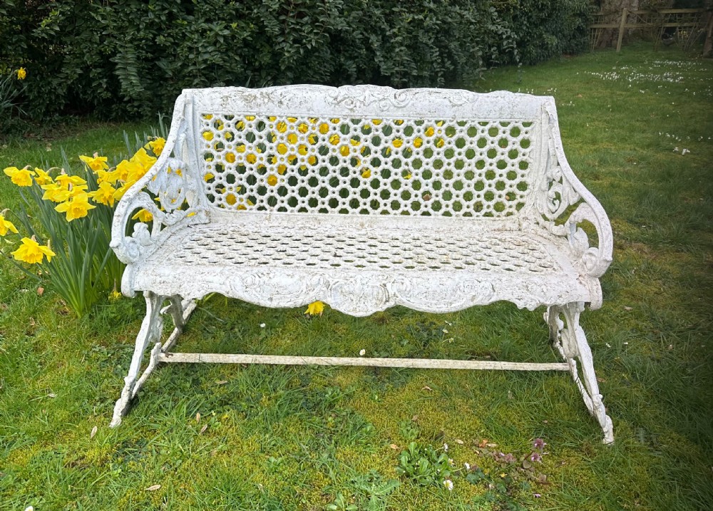 A Victorian white painted cast iron garden bench featuring a pierced lattice backrest and ornate scrolled armrests. View III