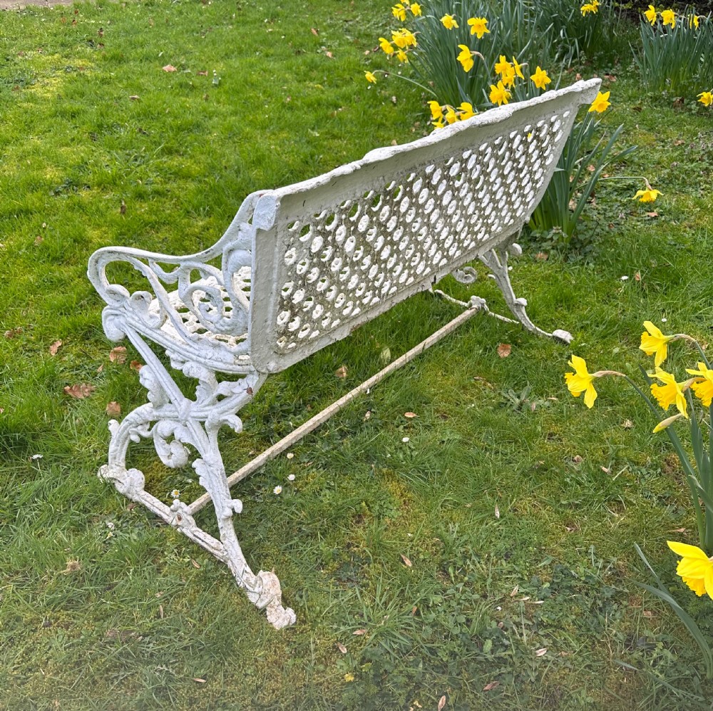 A Victorian white painted cast iron garden bench featuring a pierced lattice backrest and ornate scrolled armrests. View IV