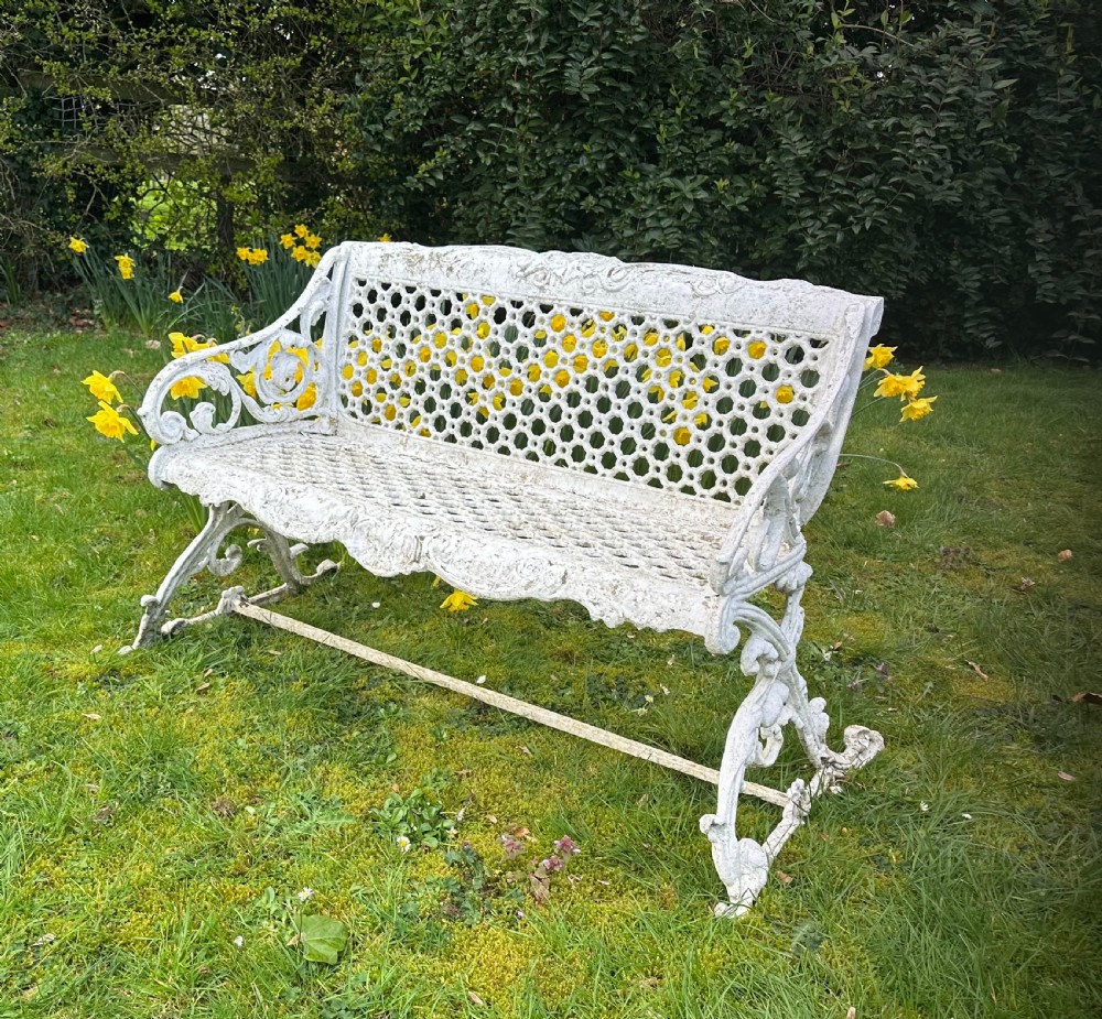 A Victorian white painted cast iron garden bench featuring a pierced lattice backrest and ornate scrolled armrests. View V