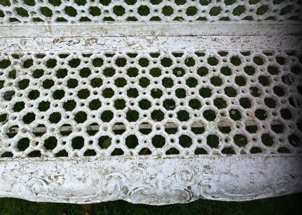 A Victorian white painted cast iron garden bench featuring a pierced lattice backrest and ornate scrolled armrests. View VII