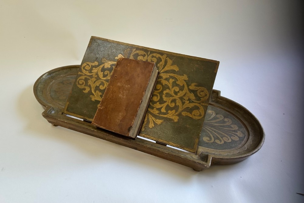 An antique Florentine painted and giltwood tabletop book stand with an open book resting on its angled surface. View V