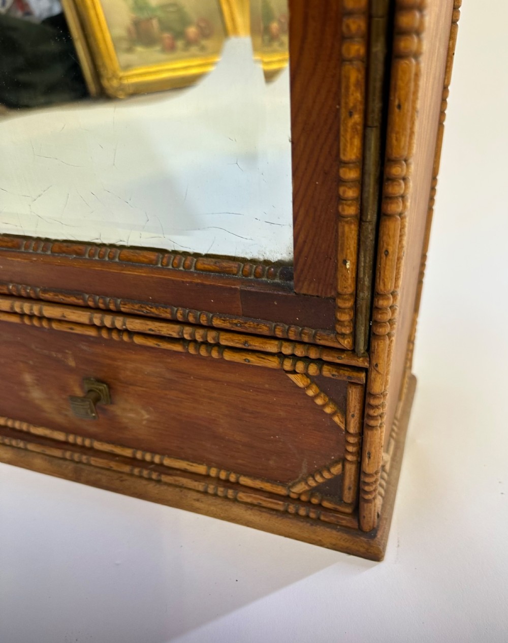 A small warm brown wooden French cabinet featuring a bevelled glass mirror door, bobbin moulding borders, a stepped pediment crest, and a lower drawer. View II