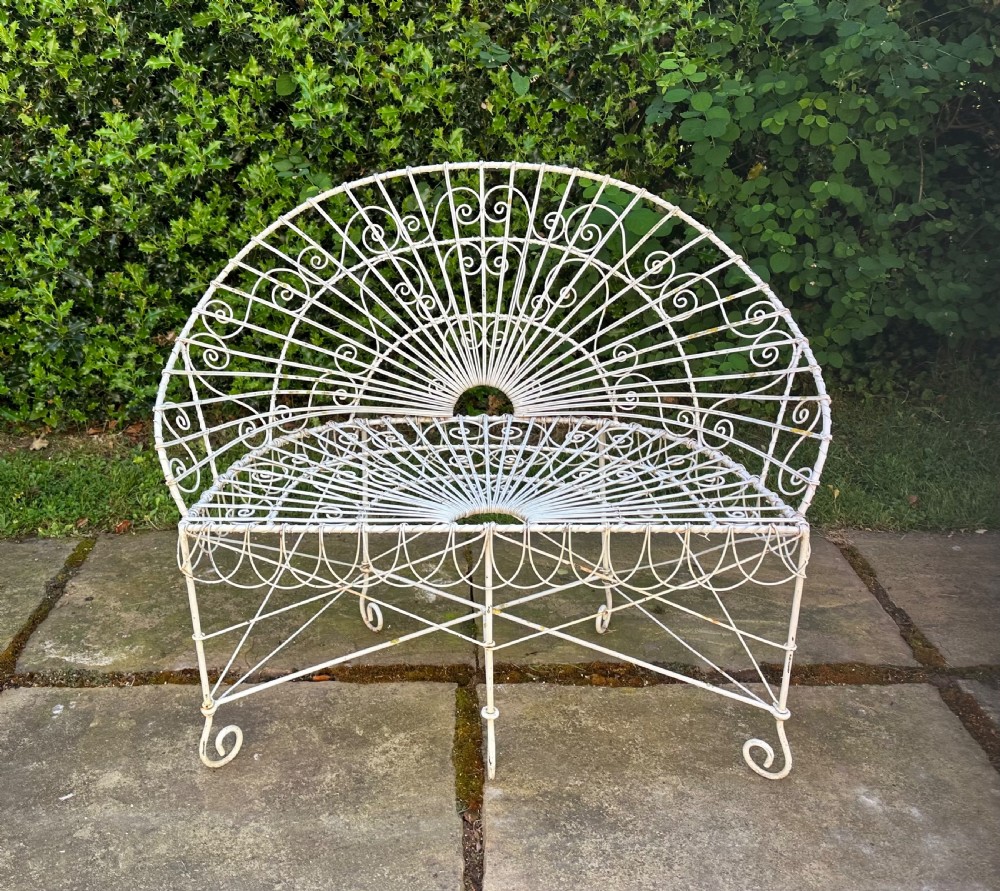 A three-piece white painted wrought iron wirework garden set featuring a bench and two matching armchairs with arched fan-back designs. View IV