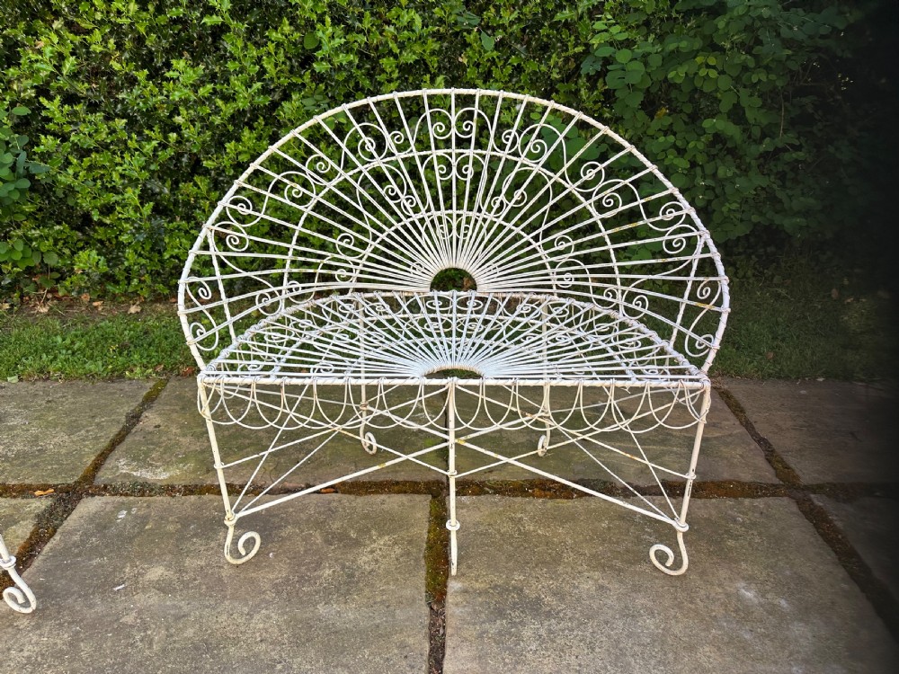 A three-piece white painted wrought iron wirework garden set featuring a bench and two matching armchairs with arched fan-back designs. View V