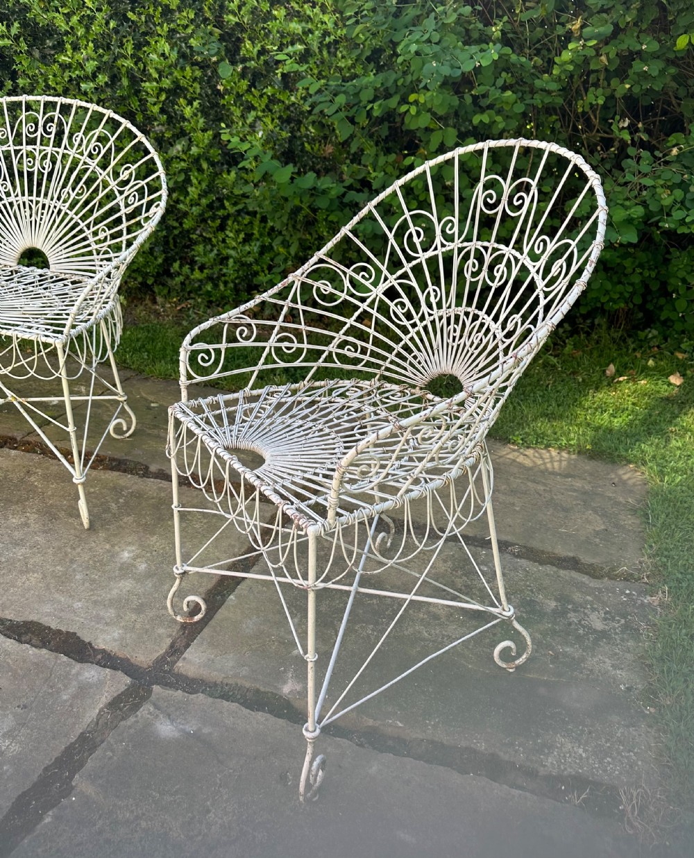 A three-piece white painted wrought iron wirework garden set featuring a bench and two matching armchairs with arched fan-back designs. View VII