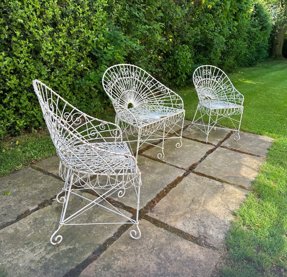 A three-piece white painted wrought iron wirework garden set featuring a bench and two matching armchairs with arched fan-back designs. View VIII