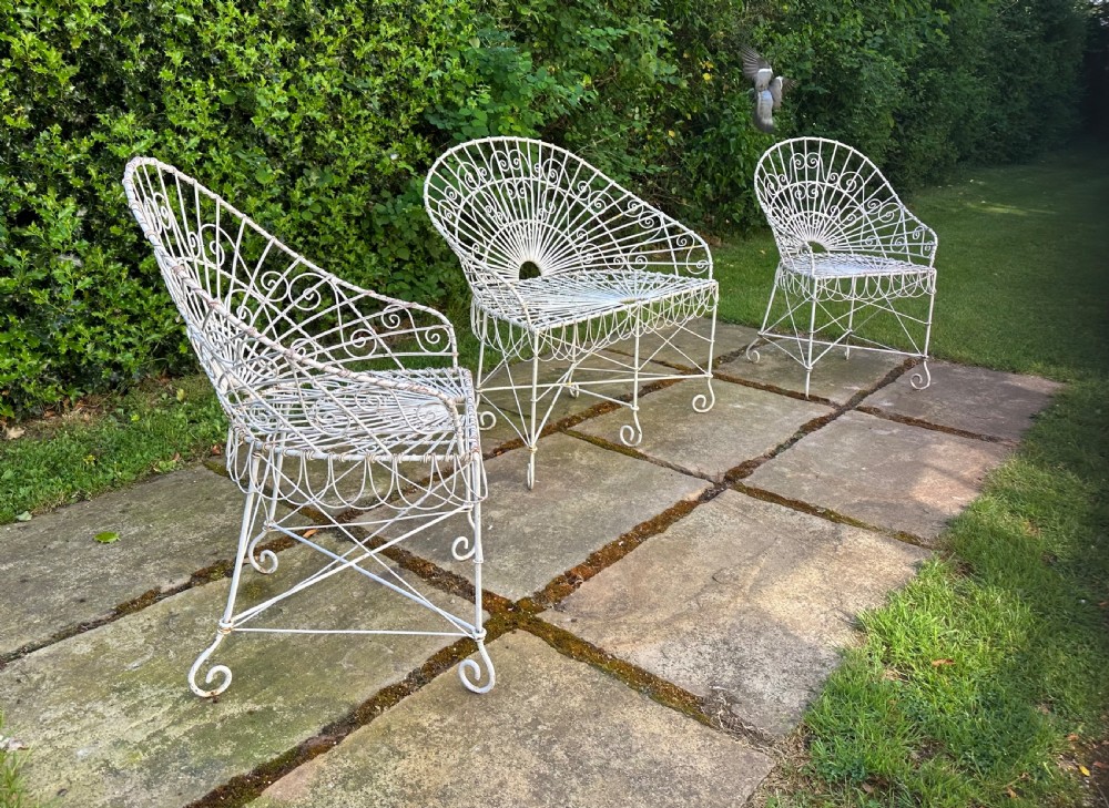 A three-piece white painted wrought iron wirework garden set featuring a bench and two matching armchairs with arched fan-back designs. View IX