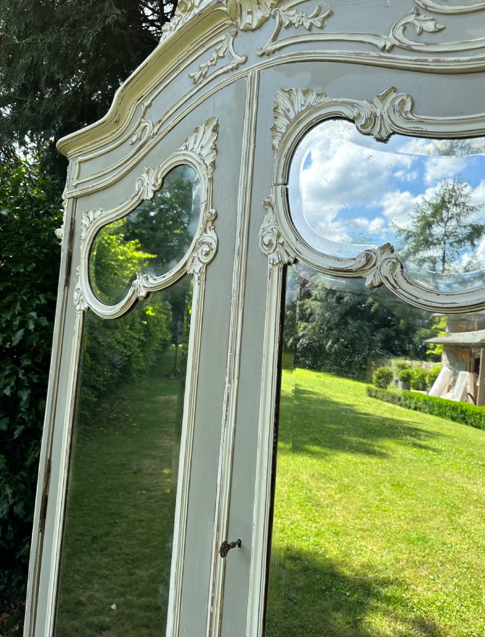 A grey and off-white painted French armoire featuring double mirrored doors and an ornate carved Rococo cresting. View VII