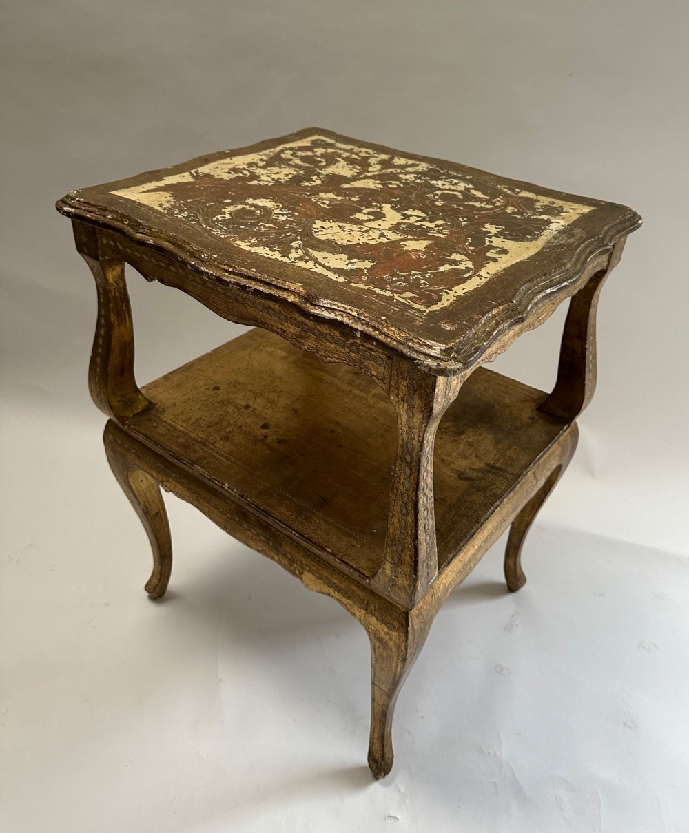 A two-tiered Italian Florentine side table with a distressed gold leaf finish, cabriole legs, a scalloped apron, and decorative top surface detailing. View II