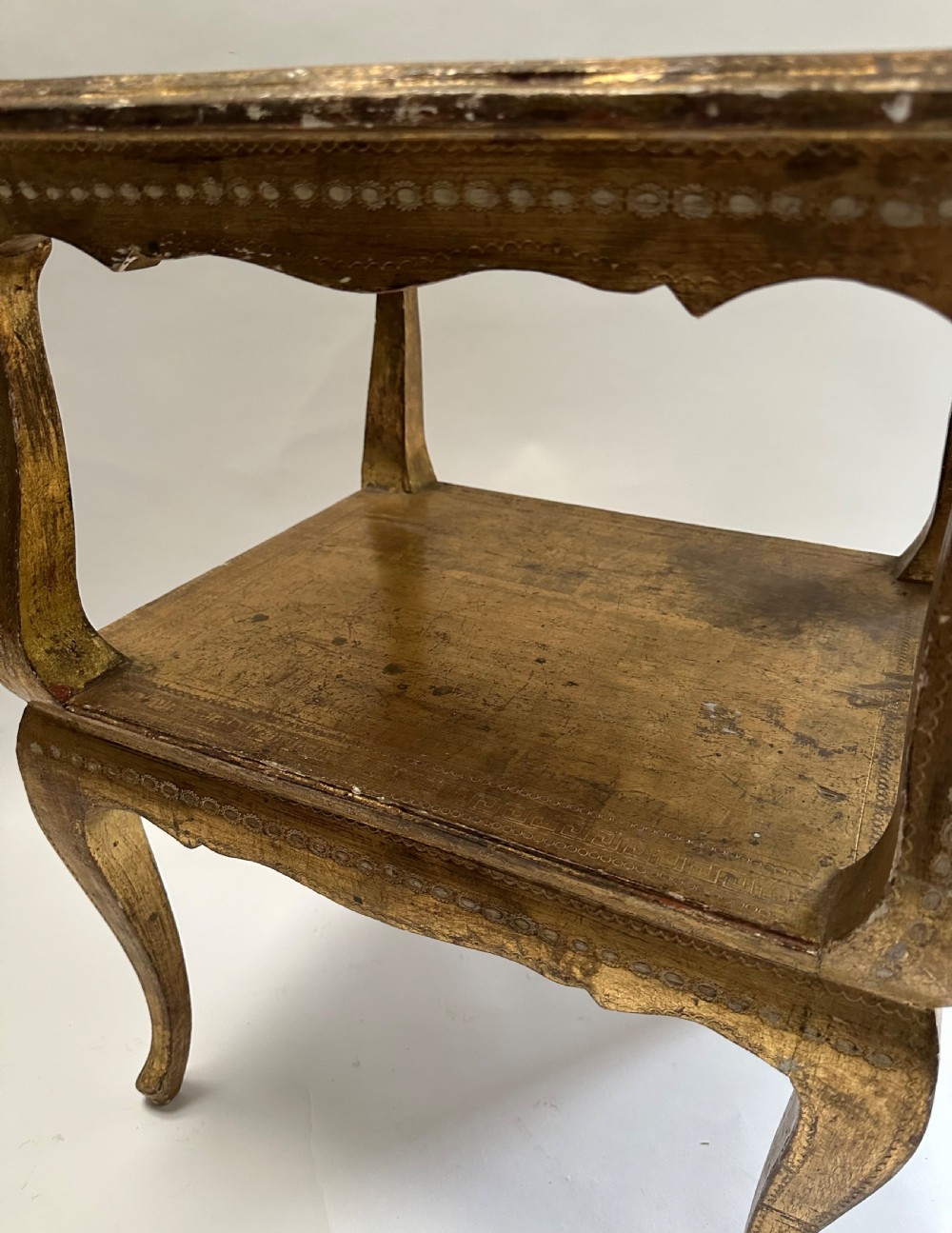 A two-tiered Italian Florentine side table with a distressed gold leaf finish, cabriole legs, a scalloped apron, and decorative top surface detailing. View III