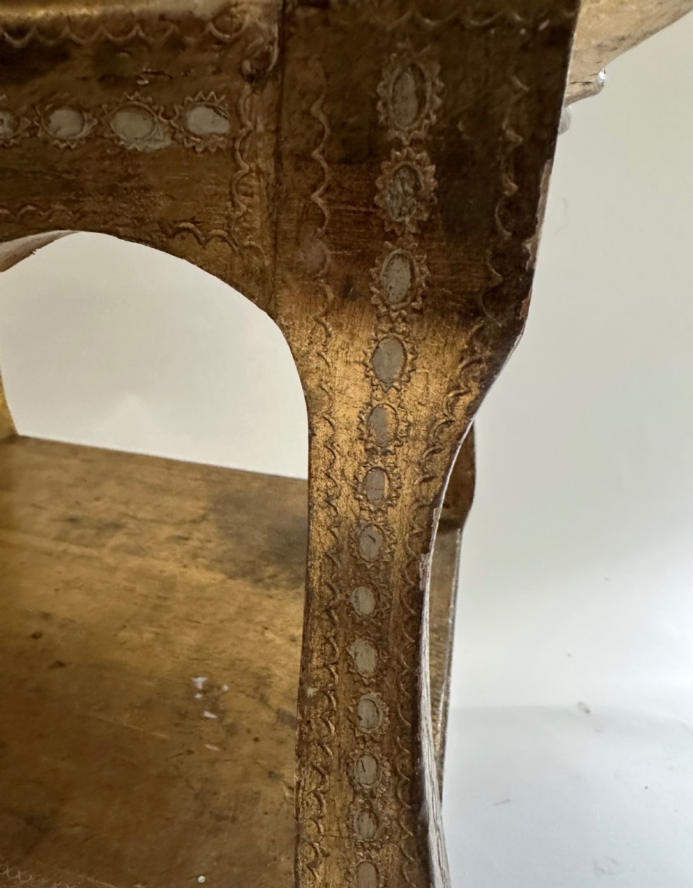 A two-tiered Italian Florentine side table with a distressed gold leaf finish, cabriole legs, a scalloped apron, and decorative top surface detailing. View V