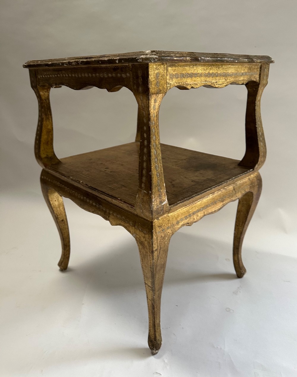 A two-tiered Italian Florentine side table with a distressed gold leaf finish, cabriole legs, a scalloped apron, and decorative top surface detailing. View IX