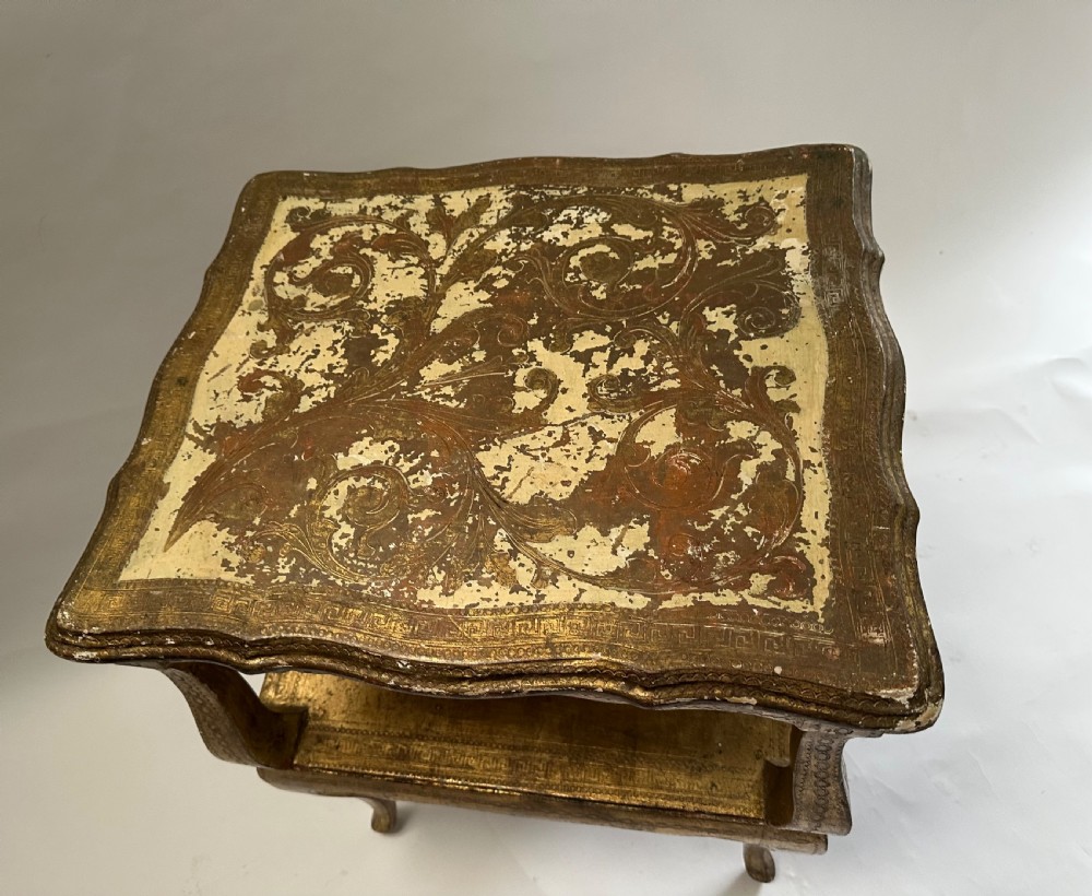 A two-tiered Italian Florentine side table with a distressed gold leaf finish, cabriole legs, a scalloped apron, and decorative top surface detailing. View X