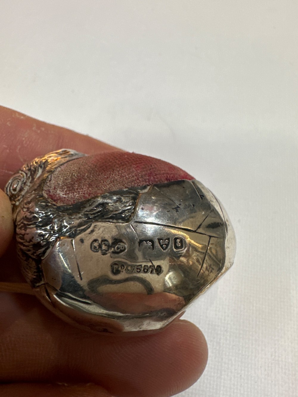 An Edwardian sterling silver novelty pin cushion modelled in the form of a chick hatching from an egg with a dark red velvet insert. View V