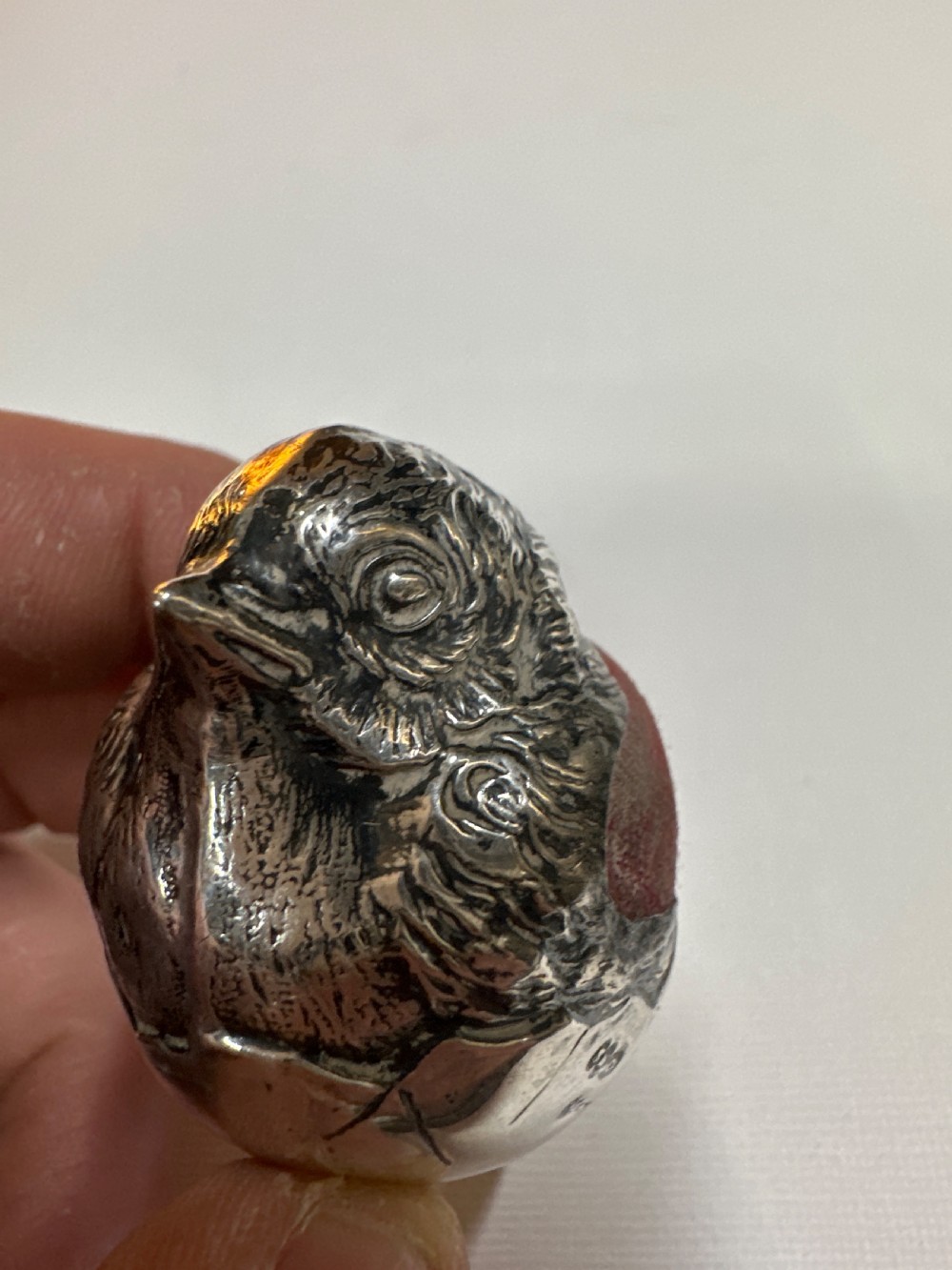 An Edwardian sterling silver novelty pin cushion modelled in the form of a chick hatching from an egg with a dark red velvet insert. View VII