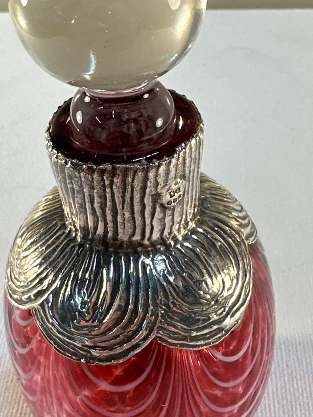 A patterned red glass perfume bottle featuring an embossed Irish silver collar and a round clear glass stopper. View III