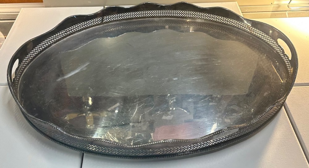 An oval silver-plated serving tray with a pierced reticulated gallery rim, scalloped border, and integrated side handles.