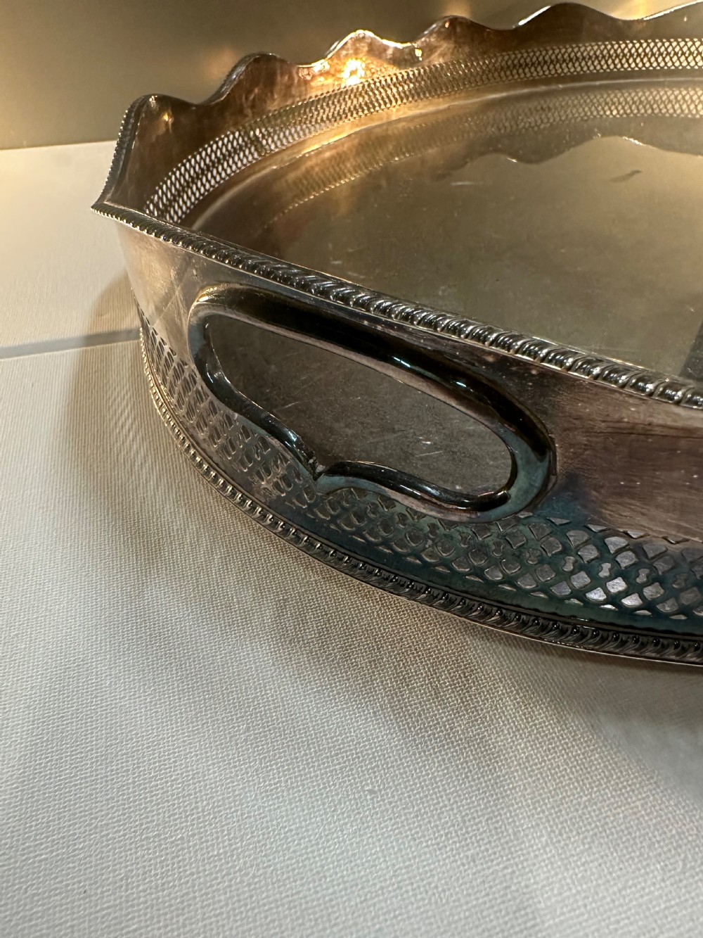 An oval silver-plated serving tray with a pierced reticulated gallery rim, scalloped border, and integrated side handles. View IV