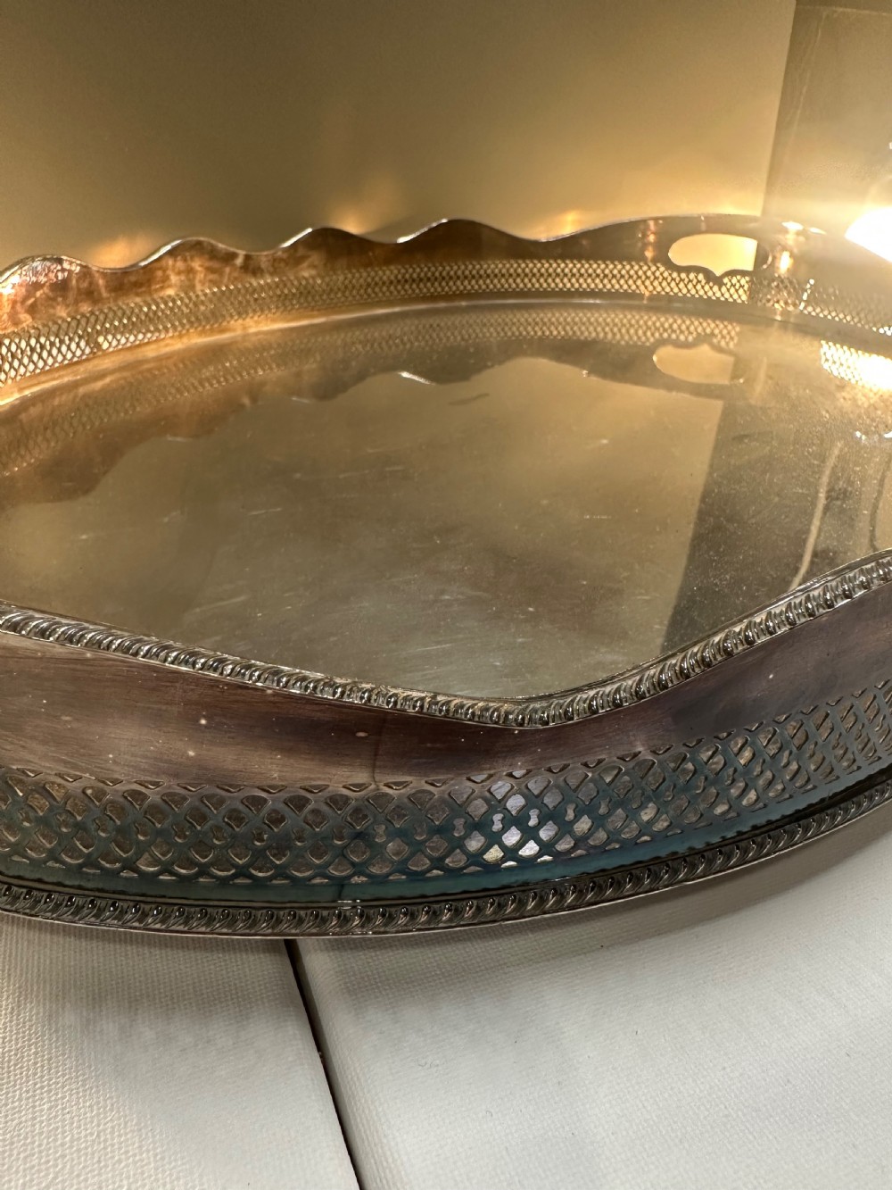 An oval silver-plated serving tray with a pierced reticulated gallery rim, scalloped border, and integrated side handles. View V