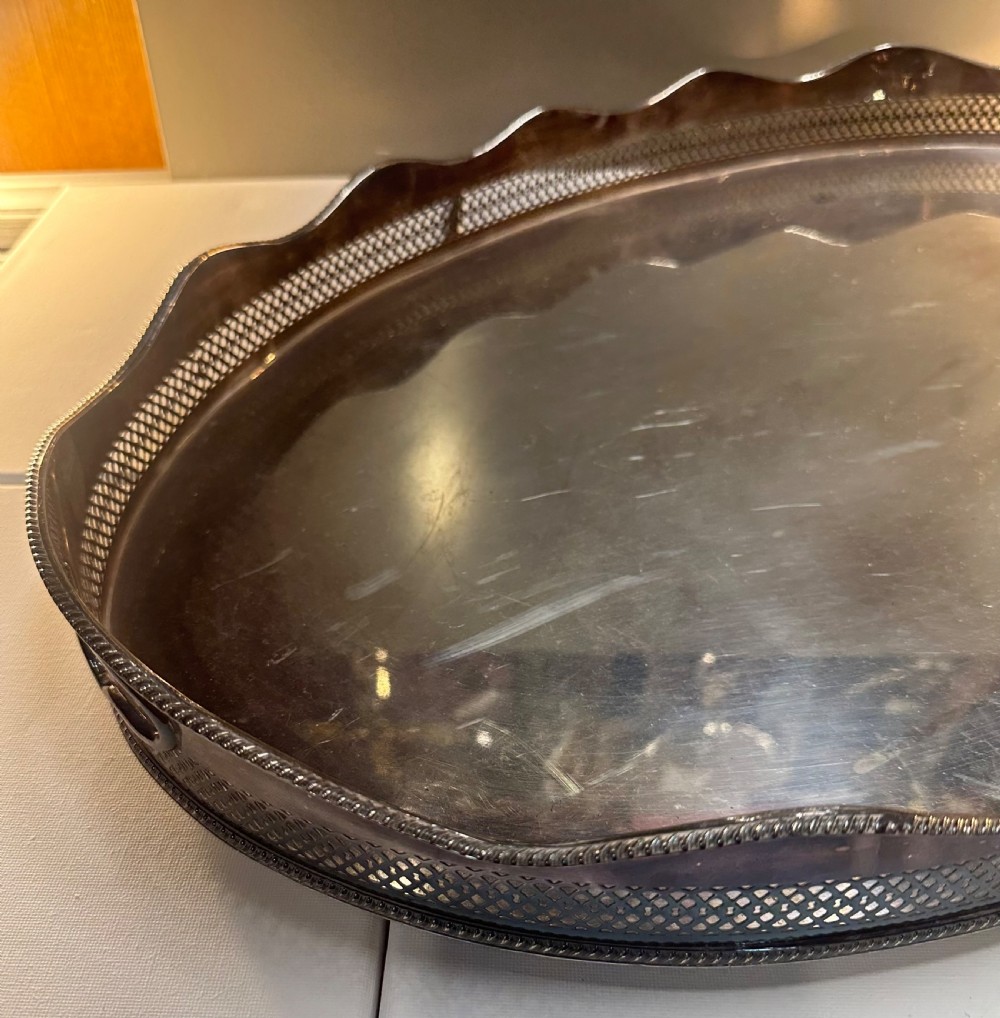 An oval silver-plated serving tray with a pierced reticulated gallery rim, scalloped border, and integrated side handles. View VI