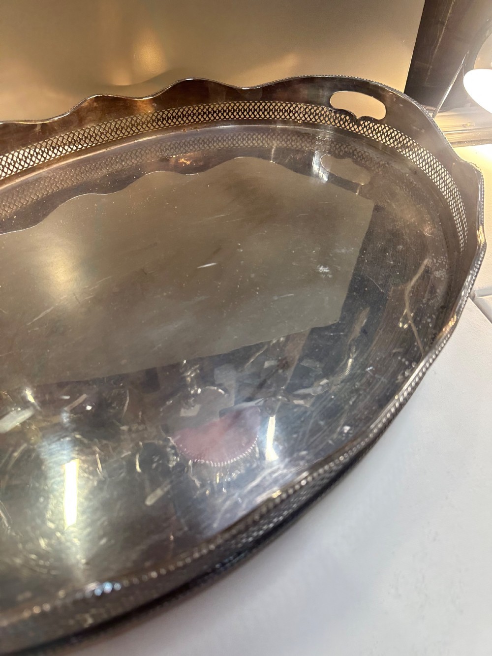 An oval silver-plated serving tray with a pierced reticulated gallery rim, scalloped border, and integrated side handles. View VII