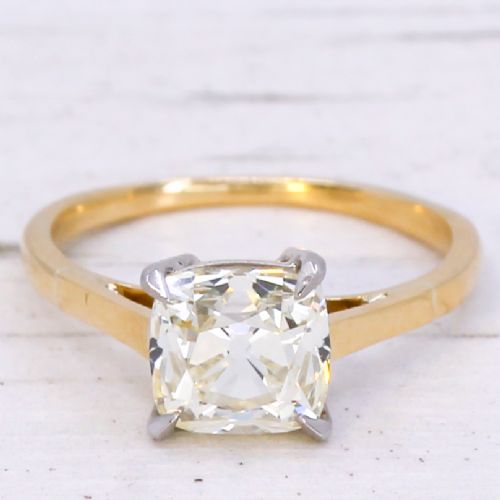 fig 2. A vintage solitaire engagement ring featuring an old cut cushion diamond held in platinum claws on a tapered yellow gold band.