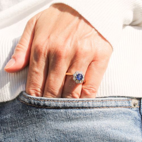 fig 1. A yellow gold vintage ring featuring a central round blue sapphire encircled by a halo of brilliant-cut diamonds.
