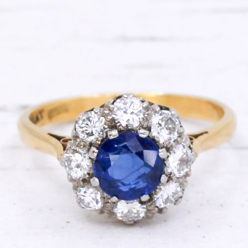fig 2. A yellow gold vintage ring featuring a central round blue sapphire encircled by a halo of brilliant-cut diamonds.