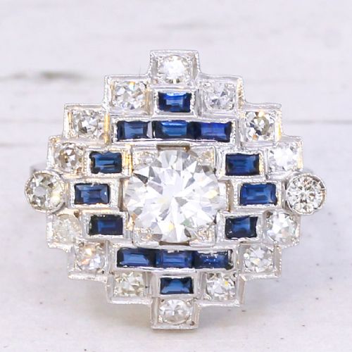 fig 2. An Art Deco diamond and sapphire cluster ring featuring a central brilliant-cut diamond surrounded by geometric borders of blue sapphires and smaller diamonds.