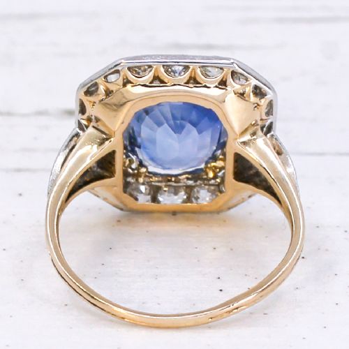 An antique Edwardian cluster ring featuring a central cushion-cut blue Ceylon sapphire surrounded by a halo of diamonds set in platinum and yellow gold. View V