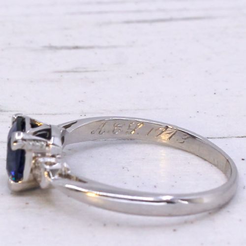 fig 3. A platinum ring featuring a central cushion-cut blue sapphire held in a claw setting, flanked by a small round diamond on each shoulder.