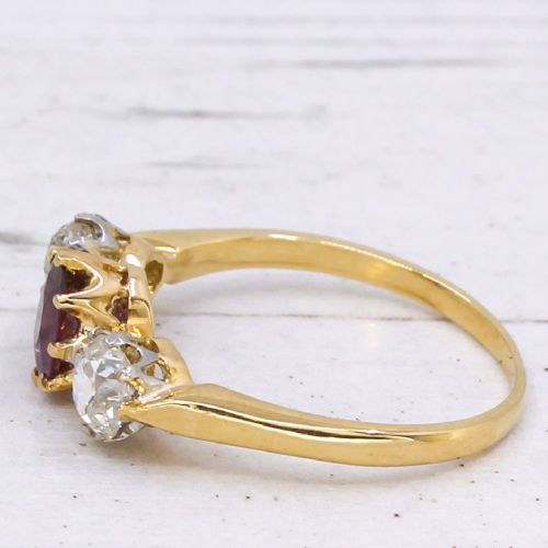 fig 3. An antique yellow gold trilogy ring featuring a central cushion-cut red ruby flanked by two old-cut diamonds in claw settings.