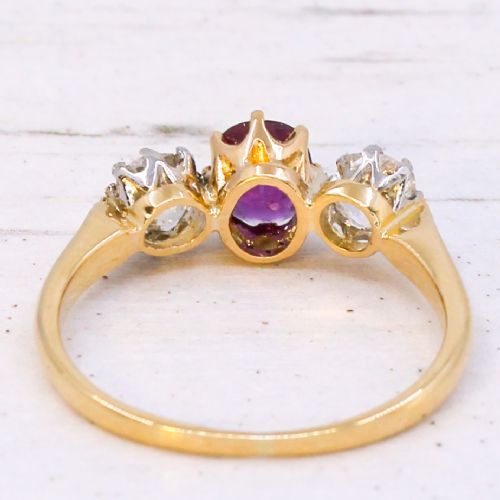 An antique yellow gold trilogy ring featuring a central cushion-cut red ruby flanked by two old-cut diamonds in claw settings. View V