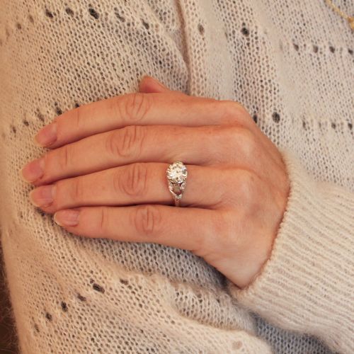 fig 1. A vintage mid-century platinum engagement ring featuring a central round brilliant cut diamond flanked by baguette and round accent stones.