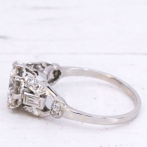 fig 3. A vintage mid-century platinum engagement ring featuring a central round brilliant cut diamond flanked by baguette and round accent stones.