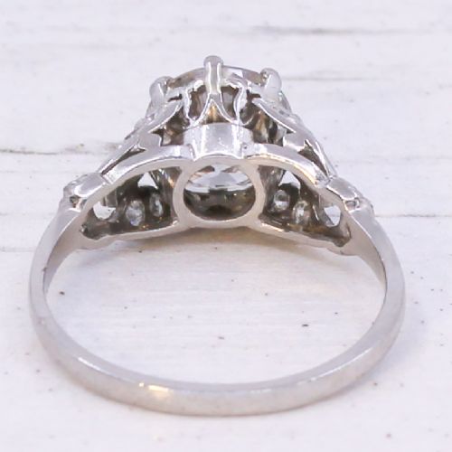 A vintage mid-century platinum engagement ring featuring a central round brilliant cut diamond flanked by baguette and round accent stones. View V