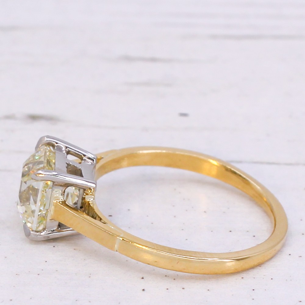 A vintage solitaire engagement ring featuring an old cut cushion diamond held in platinum claws on a tapered yellow gold band. View IV