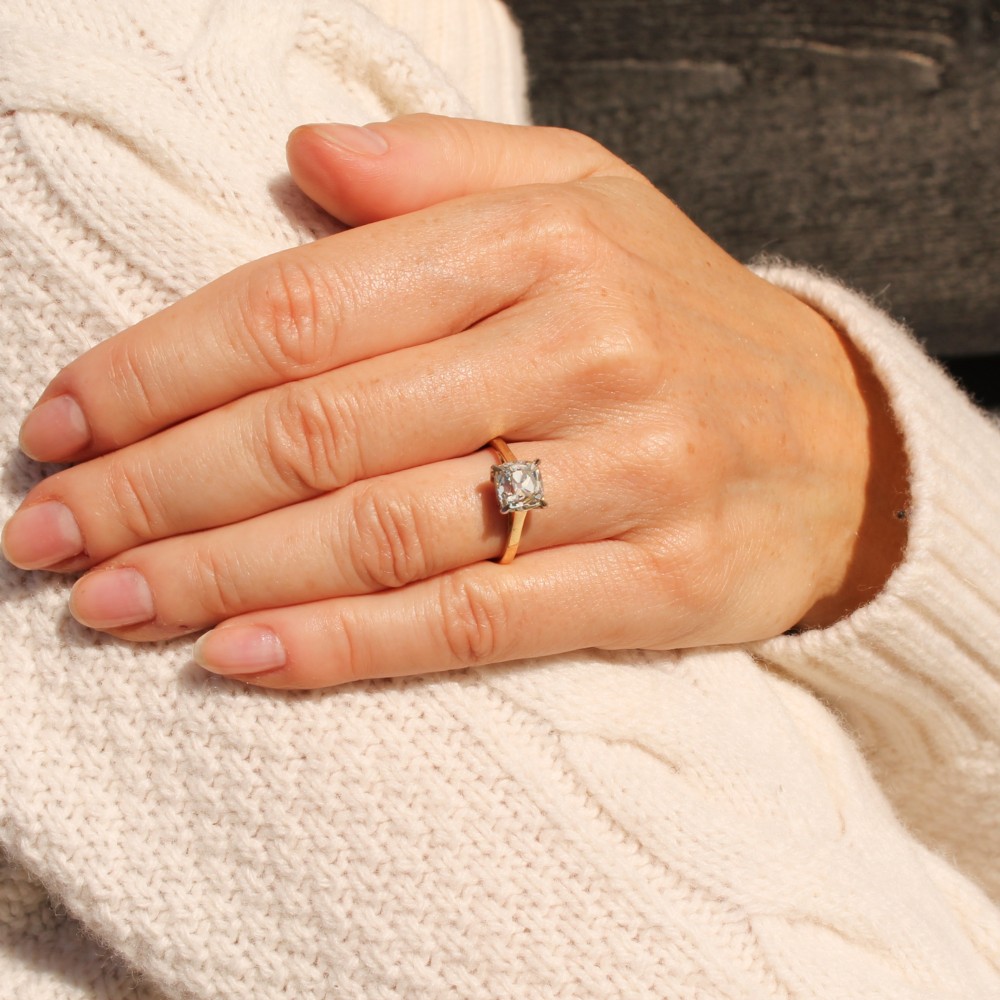 A vintage solitaire engagement ring featuring an old cut cushion diamond held in platinum claws on a tapered yellow gold band. View VI